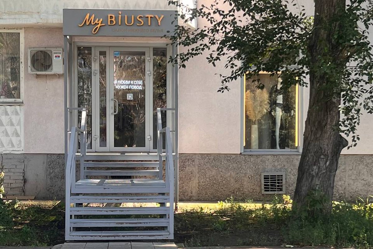 Вход в салон в жилом доме, над дверью вывеска, крыльцо с перилами